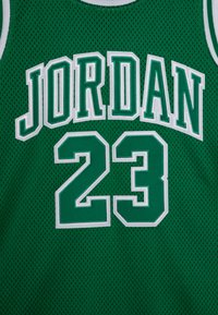 Zelený basketbalový dres s priedušnou sieťovinou. Na prednej strane je vyšitý nápis "JORDAN" a číslo "23" v bielych, blokových písmenách.
