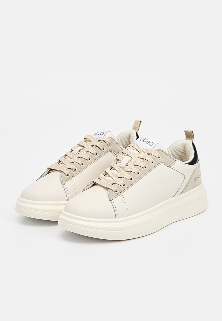 Beżowe sneakersy z gładkiej skórzanej cholewki, okrągłym noskiem i lekko wyściełanym językiem. Posiadają kontrastujące czarne akcenty na pięcie i logo.