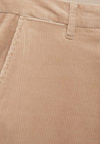 Svijetlosmeđi kord fabric sa vertikalnim rebrima, s bočnim džepovima i petljom za remen, prikazuje glatku teksturu.