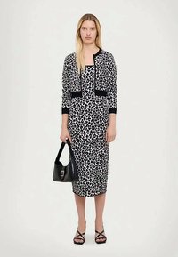 Φούστα με μαύρο και άσπρο λεοπάρ σχέδιο, σε συνδυασμό με μια μαύρη κοντομάνικη ζακέτα. Αξεσουάρ περιλαμβάνουν μια μαύρη τσάντα και σανδάλια με λουριά.