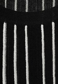 Tessuto nero con strisce bianche verticali, caratterizzato da un motivo a maglia testurizzata. Il colletto è nero, sottolineando il design a strisce.