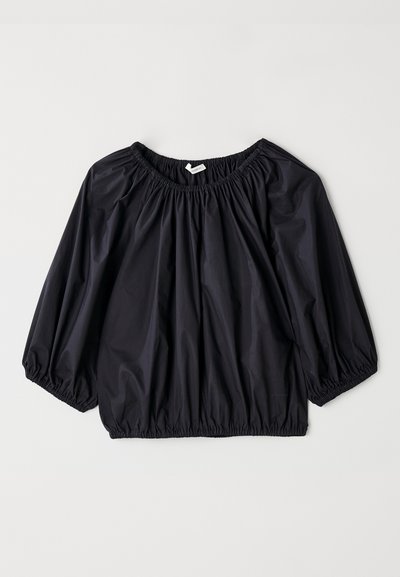 Musta, kevyt pusero, jossa on elastisoitu kaula-aukko ja hihansuunsuukkeet. Ominaisuuksiin kuuluu löysä, ilmapallo-tyylinen muoto ja sileä, kiiltävä pinta.