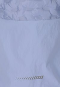 Ljusblått puffjacka med en texturerad, kviltad övre sektion och en slät nedre sektion, som har en reflekterande randdesign vid fållen.