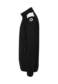 Sort jakke med høj krave, hvide skulderdetaljer og et lille logo på venstre arm. Har en sidelomme med lynlås til opbevaring.