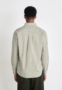 Camicia a quadri verde e beige con colletto classico, maniche lunghe e un carrè sul retro, realizzata in un tessuto di cotone leggero.
