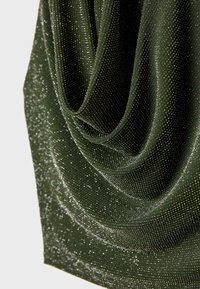 Olivgrön tyg med fina, skimrande detaljer. Materialet faller i mjuka veck och visar en texturerad yta med en subtil lyster.