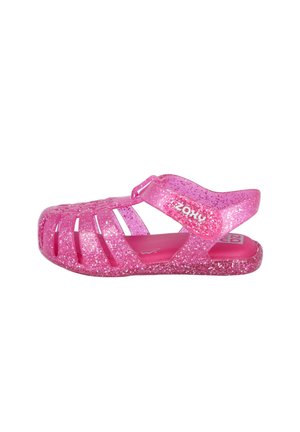 Sandalia de gelatina rosa con purpurina para niños, con punta cerrada, correa ajustable y suela texturizada, mostrada de perfil sobre fondo blanco.