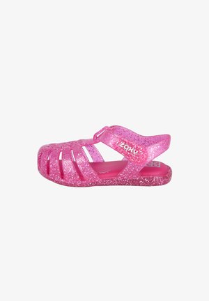 Sandalia de gelatina rosa con purpurina para niños, con punta cerrada, correa ajustable y suela texturizada, mostrada de perfil sobre fondo blanco.