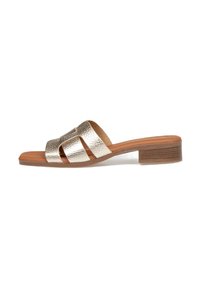 Sandalia de deslizar metálica en oro con tres tiras anchas, un tacón de bloque de madera y una plantilla de cuero suave. Suela plana para mayor comodidad.