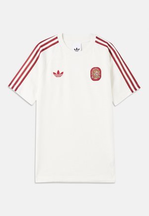 Bílý sportovní dres s červeným logem Adidas a znakem národního týmu Španělska, s třemi červenými pruhy na každém rameni.