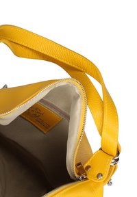 Borsa a tracolla gialla in pelle con zip aperta, che mostra l'interno in tessuto beige e un'etichetta cucita all'interno, dotata di una vasta tracolla regolabile.