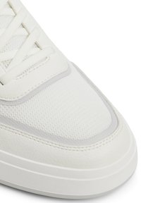 Sneaker bianco con parte superiore in rete testurizzata, dettagli in pelle liscia e lacci bianchi piatti. Punta arrotondata con dettagli di cucitura discreti.