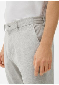 Lichtgrijze, stretchy broek met een knoopsluiting en een elastische tailleband. Bevat zijzakken en een gladde, textuurrijke stof.