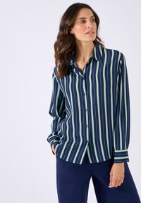 Chemise boutonnée rayée marine avec des bandes verticales vertes et bleues, manches longues et col. Tissu doux avec une coupe décontractée.