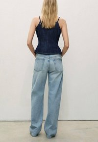 Tummansininen denim-peplumtoppiyhdistelmä vaaleansinisillä leveälahkeisilla farkuilla, joissa on rento istuvuus, kaksi takataskua ja hienovarainen haalistuma.