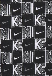 Musta kangas, millel on korduv musternäidis sõna "NIKE" erinevates hallides ja valgetes toonides koos Nike logoga.