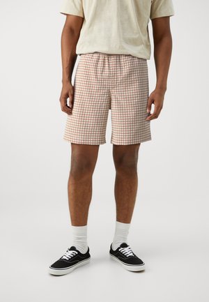 Shorts à carreaux en tissu léger, avec un motif à grille rouge et marron sur fond crème, dotés d'une taille élastique et de poches latérales.