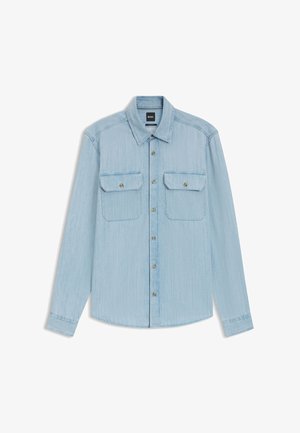 Hellblaues Denim-Hemd mit langen Ärmeln, Knopfleiste, zwei Brusttaschen mit Knöpfen und spitzem Kragen, flach auf einem weißen Hintergrund liegend.