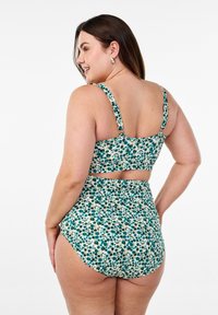 Gėlėtas bikinis, kuriame vyrauja mėlynos ir žalios spalvos raštas, su storais petnešomis, trumpu viršumi ir aukštu juosmeniu. Medžiaga yra lygi.