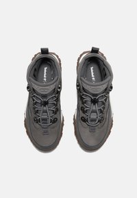 Gray hiking boots with a sturdy design, featuring a textured upper, black laces, metal eyelets, and a brown rubber sole.