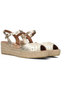 Gouden metallic espadrille sandaal met een open teen, kruislings gespen en een geweven jute platformzool. Beschikt over een gestructureerd bovenwerk ontwerp.