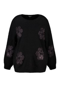 Pull noir en tissu doux et texturé avec cinq appliqués floraux scintillants à l'avant. Coupe décontractée et col rond.