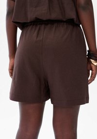 Donkerbruine katoenen shorts met een elastische tailleband, voorzien van een gladde textuur en rechte snit, die net boven de dij eindigen.