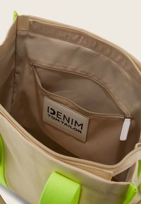 Borsa a spalla in tela beige con manici verde brillante. L'interno presenta una tasca con zip e un'etichetta con il marchio "DENIM TOM TAILOR".