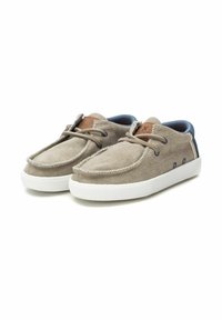 Zapatillas de lona beige con suelas de goma blanca, que presentan un interior azul en contraste, un acento de cuero marrón y costuras decorativas a lo largo de los bordes.