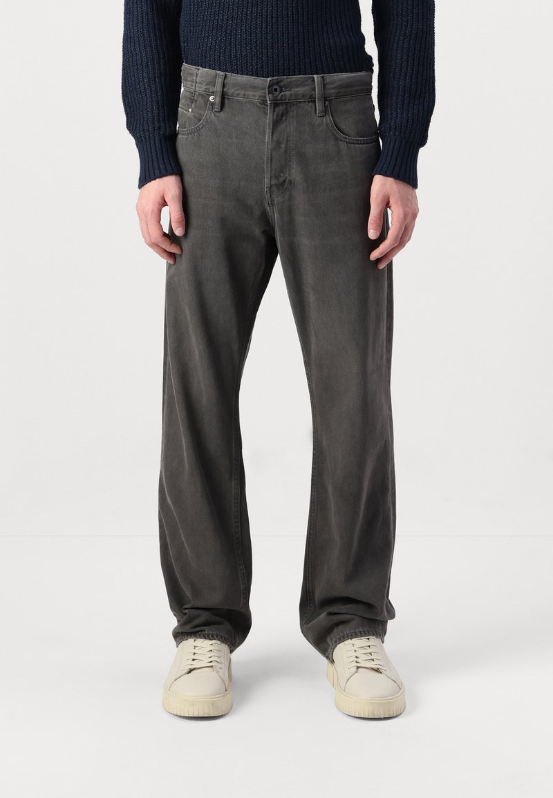 Grå denimbyxor med rak passform, femficksdesign och subtil blekning. I kombination med beige sneakers och en marinblå stickad tröja.