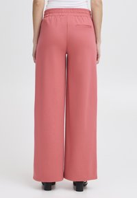 Pantaloni rosa a gamba larga con vita elastica, dotati di una tasca posteriore e una texture liscia. Progettati per il comfort e la libertà di movimento.