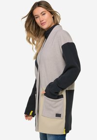 Szary, granatowy i kremowy kardigan z polaru z długimi rękawami, przednimi kieszeniami i luźnym krojem, z żółtymi akcentami na mankietach.