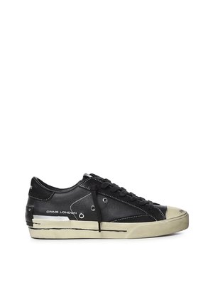 Sneaker nera a taglio basso con suola bianca, lacci neri, punta bianca e testo ""Crime London"" sul lato.