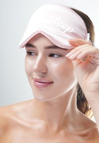 Rosa satinögonmask med vit text "Sleep"; konturerad design som passar ansiktets kurvor, mjuk textur för komfort, justerbart resårband.