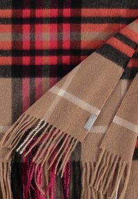 Plaid scarf in shades of red, black, and beige. Soft fabric with fringed ends and a tag featuring logo. Distinctive checkered pattern.