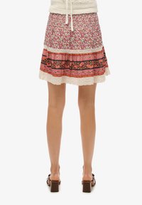 Falda de flores multicolor con borde de encaje, que presenta una cinturilla estampada en rosa y naranja, y un diseño acampanado y con capas.
