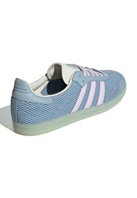 Svijetloplave tenisice od mrežaste tkanine, s bijelim kožnim detaljima, tri ružičaste pruge i prozirnim gumenim potplatom. Cipele imaju zaobljen vrh i ravne vezice.