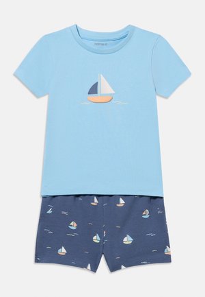 Chemise à manches courtes bleu clair avec un motif de voilier et short bleu marine orné de petits voiliers et d'accents de vagues.