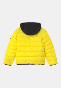 Žlutá péřová bunda s černou kapucí, prošívaný design, žebrované manžety a elastický lem. Hladký materiál, lehká konstrukce.