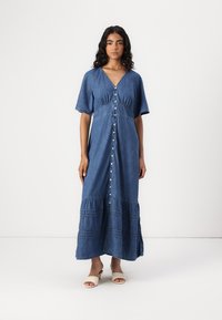 Denim maksi haljina kratkih rukava, V-izreza, s prednjim dugmadi i nabranim detaljima na struku i rubu. Svijetloplava boja, mekana tekstura.