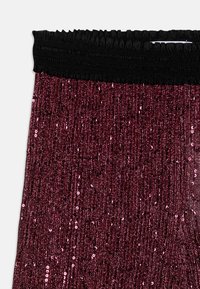 Bordeauxfärgade paljettleggings med svart elastiskt midjeband. Har vertikala paljetter som skapar en texturerad glansig effekt.