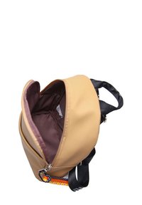 Mochila marrón con una correa negra, que cuenta con una abertura con cremallera y un forro marrón. Destacada por un acento estampado cerca de la base.