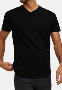 T-shirt nera a scollatura a V realizzata in tessuto morbido. Maniche corte e design aderente. Nessun motivo o grafica. Stile semplice e classico.