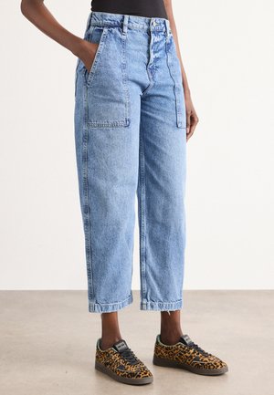 Lichtblauwe, high-waisted denim cargo broek met twee voorzakken. Heeft cropped pijpen en een relaxte pasvorm. Gecombineerd met gestructureerde sneakers.