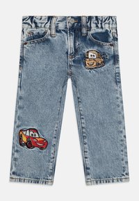 Jeans de ganga em azul claro com dois desenhos de carros de cartoon bordados na frente. Apresenta bolsos standard e um fecho de botão na cintura.