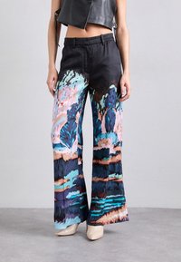 Pantalon noir avec des motifs abstraits colorés en bleu, rose et marron. Il présente une coupe droite avec une texture de tissu lisse.