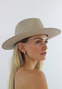 Beige Strohhut mit breiter Krempe und glatter Textur, mit einer strukturierten Krone und einem einfachen, klassischen Design.