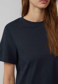 Granatowa bawełniana koszulka z okrągłym dekoltem, krótkimi rękawami i gładką teksturą. Starannie wykończone brzegi.