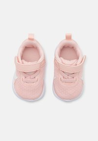 Baskets en mesh rose avec accents blancs, bande Velcro, design à bout rond et tissu texturé. Comprend un petit tirant pour un enfilage facile.
