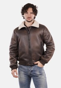 Giubbotto bomber in pelle marrone con colletto in ecopelliccia crema, chiusura con zip e polsini a coste. Presenta tasche laterali e una finitura liscia.